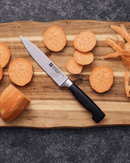 Couteau à trancher ZWILLING Four Star sur une planche en bois avec des morceaux de carottes.