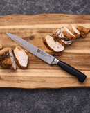 Couteau à trancher ZWILLING Four Star sur une planche en bois avec de la viande tranchée.
