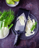 Mandoline en V avec lame à julienne, utilisée pour trancher des légumes frais sur un plateau.