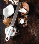 Zesteur Premium Classic Microplane grating fresh coconut on a wooden surface with coconut shells.