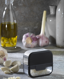 Coupe ail Microplane avec gousses d'ail et huile d'olive en arrière-plan, idéal pour râper l'ail facilement.