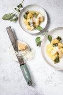 Zesteur Premium Classic Microplane with grated cheese over pasta dishes and garnished with sage leaves.