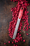 Zesteur Premium Classic Microplane grater on a bed of raspberries for culinary precision and elegance.