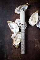 Zesteur Premium Classic Microplane positioned on fresh oysters, showcasing its precise design for culinary excellence.