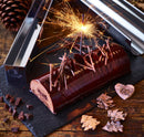 Gouttière à bûche ronde inox 30 cm avec bûche chocolat décorée de feux d'artifice sur fond rustique.